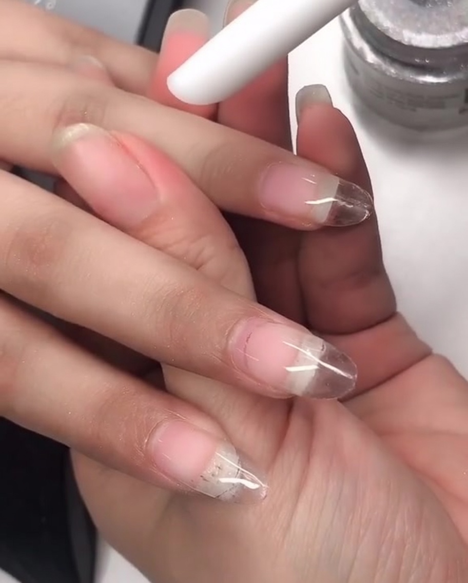 Ein Silikon-Applikator wird verwendet, um Laser-Chrome-Puder auf den Nagel zu reiben.