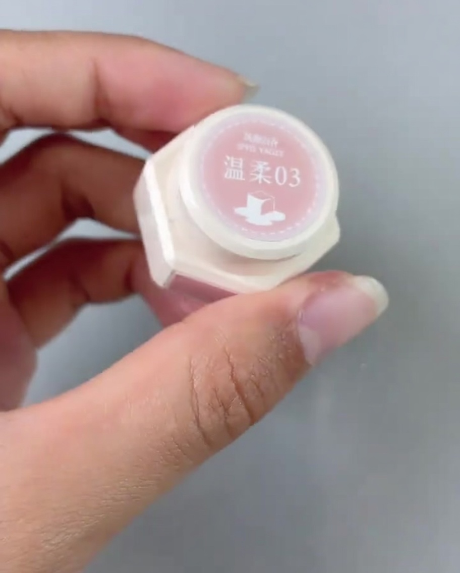Ein Pinsel trägt pinkes Gel-Polish auf den hinteren Bereich eines Nageltips auf.