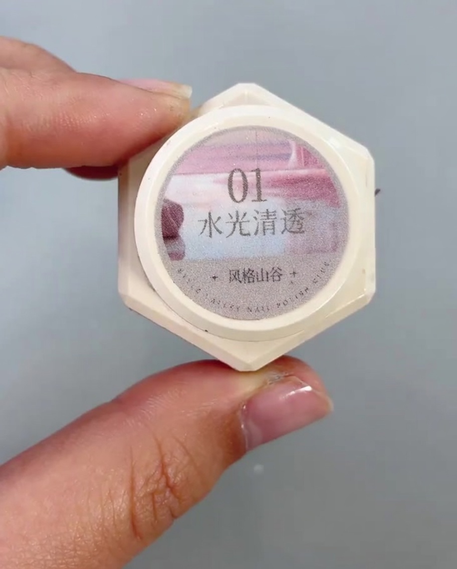 Ein Nagelpinsel trägt ein klares, schimmerndes Cat-Eye-Gel auf die untere Hälfte eines Nagels auf.