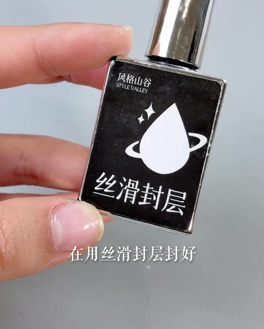 Ein Pinsel trägt einen glänzenden, klaren Top Coat über das fertige Nageldesign auf.