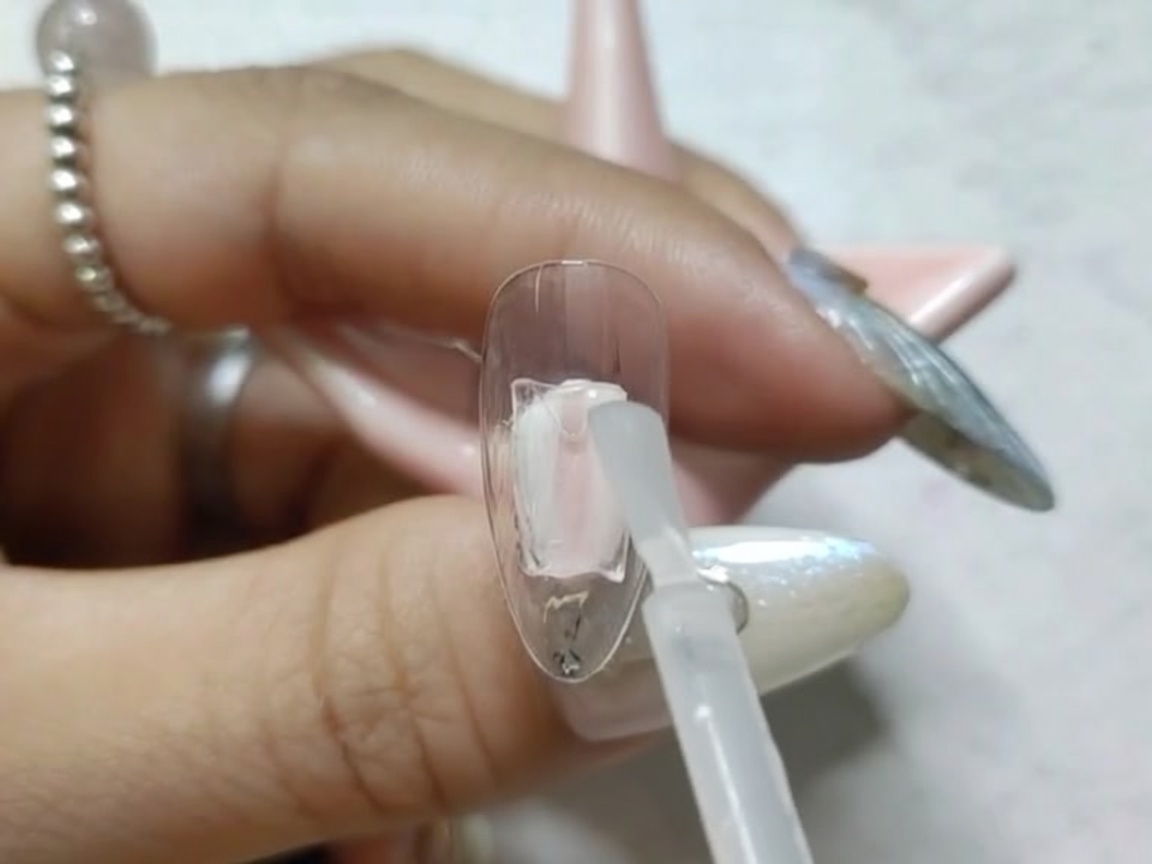 Ein Nagel-Tip im Inneren einer kleinen UV/LED-Lampe zur Aushärtung.