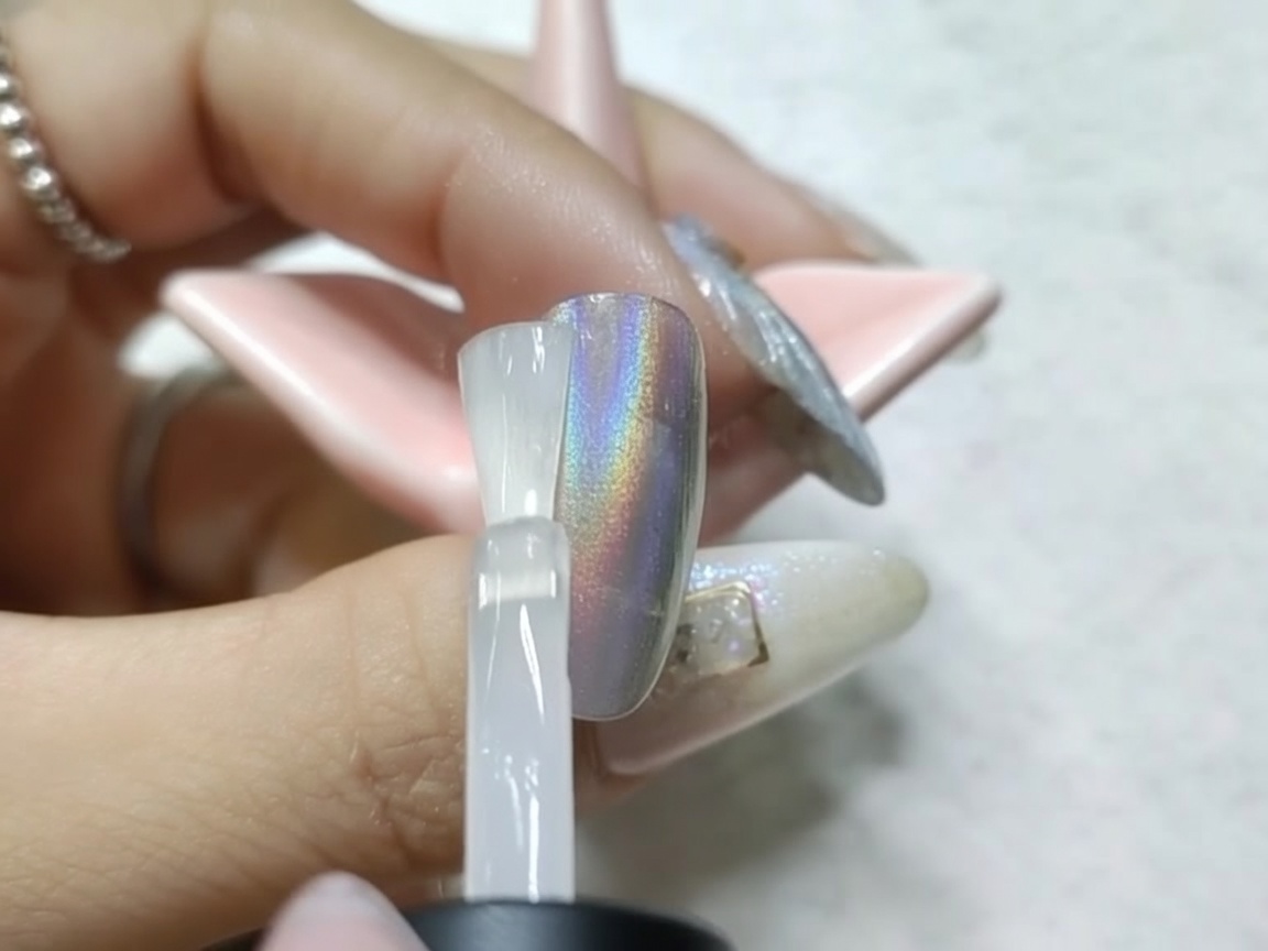 Ein mit Chrome versehener Nagel unter der UV/LED-Lampe nach dem Auftragen des matten Überlacks.