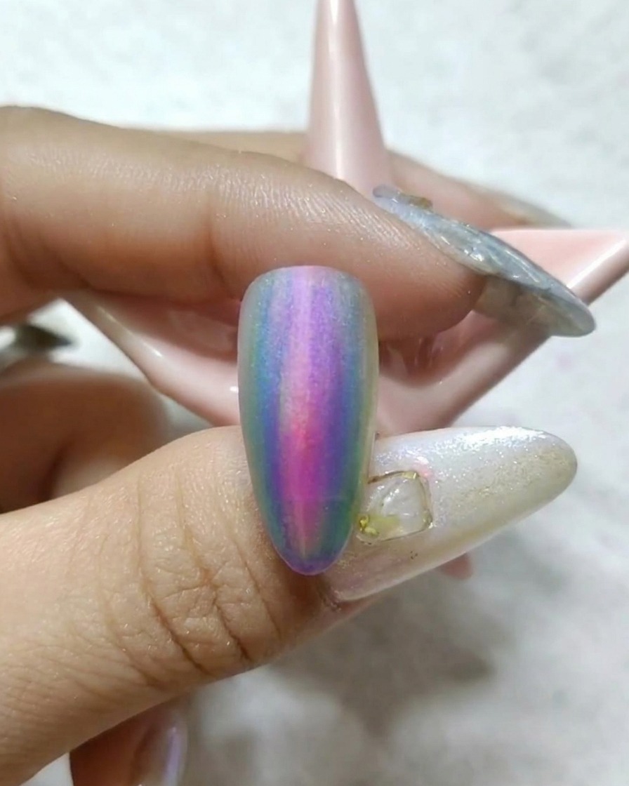 Ein Pinsel malt einen gelben Strich auf die Seite eines Nagels mit bereits vorhandenem Farbverlauf.