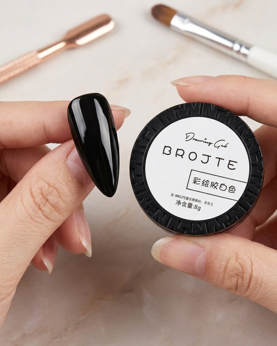 Ein kleiner schwarzer Tiegel mit weißem Malgel, im unscharfen Hintergrund sind Nailart-Pinsel zu sehen.