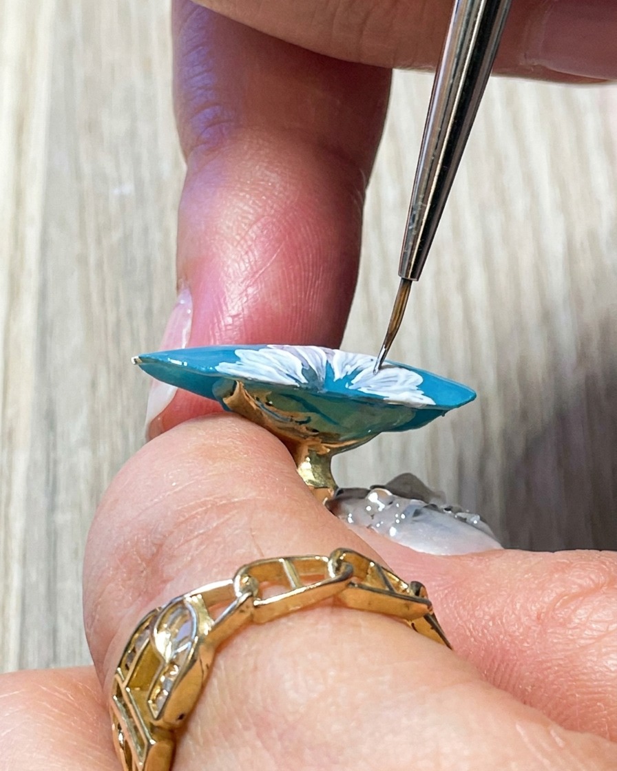 Nahaufnahme eines Pinsels, der weitere feine weiße Details im Zentrum der Gänseblümchen-Blüte hinzufügt.