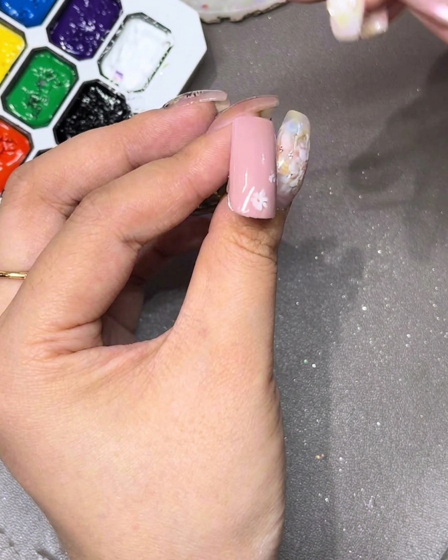 Nahaufnahme eines Nagels, auf dem das erste weiße Blütenblatt oben gezeichnet wird.