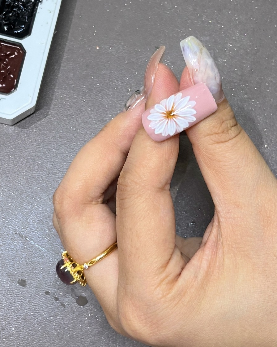 Ein schwarzer Gel-Punkt wird vorsichtig in die Mitte der weißen, geschichteten Blume gesetzt.