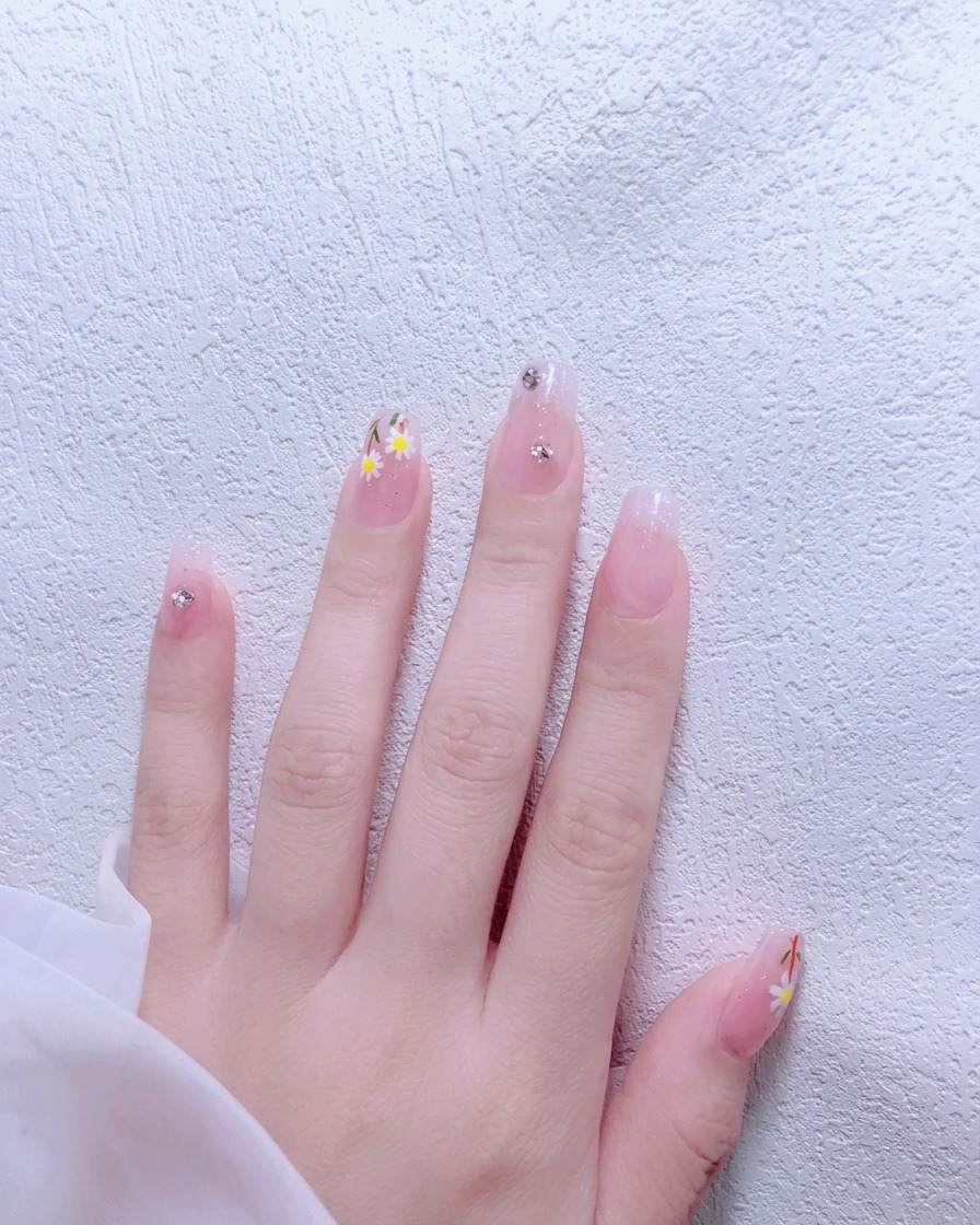 Ein Pinsel trägt nude-rosa Gel-Nagellack auf einen Fingernagel auf.