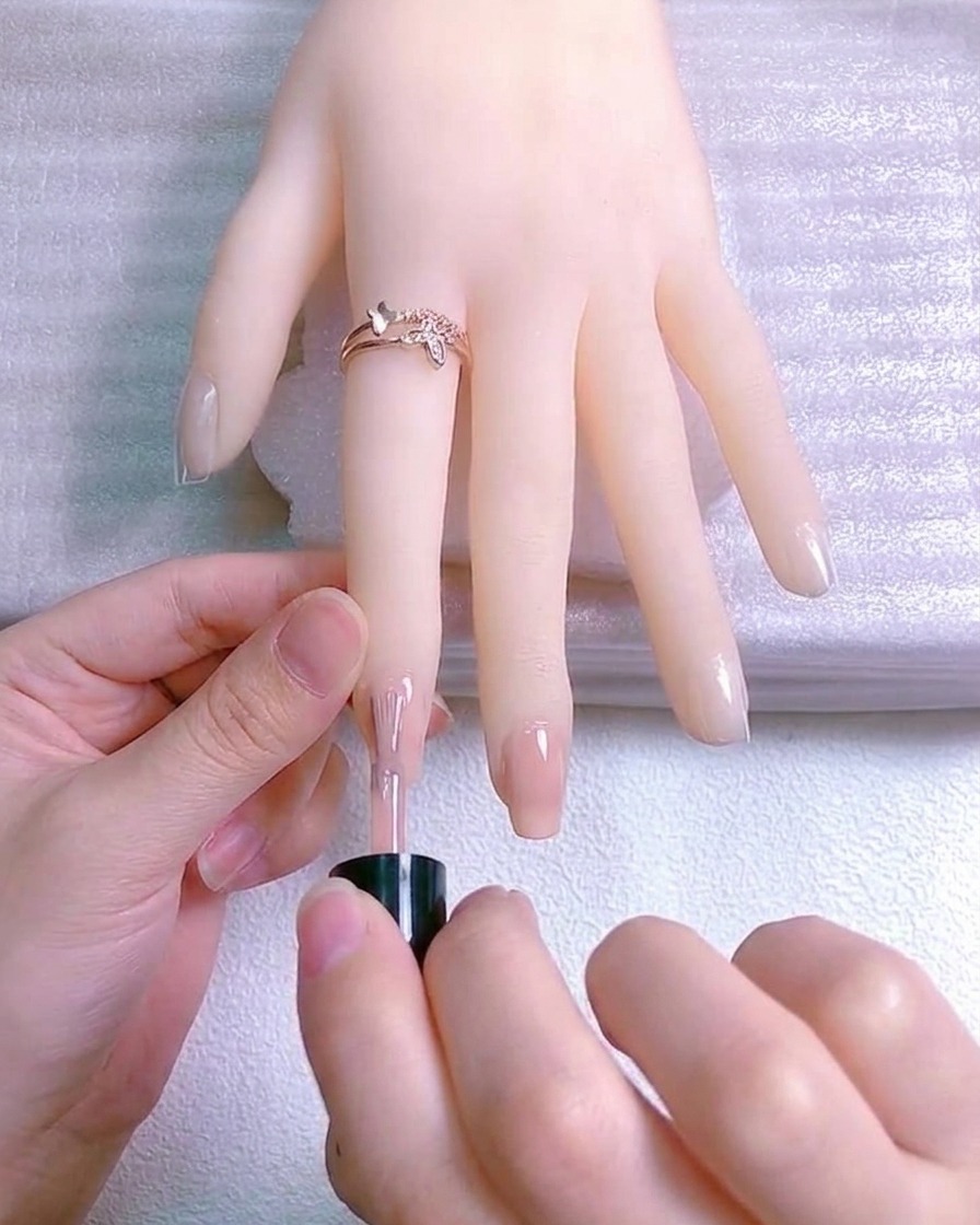 Eine dünne Schicht reflektierender Glitzerlack auf der freien Nagelspitze.
