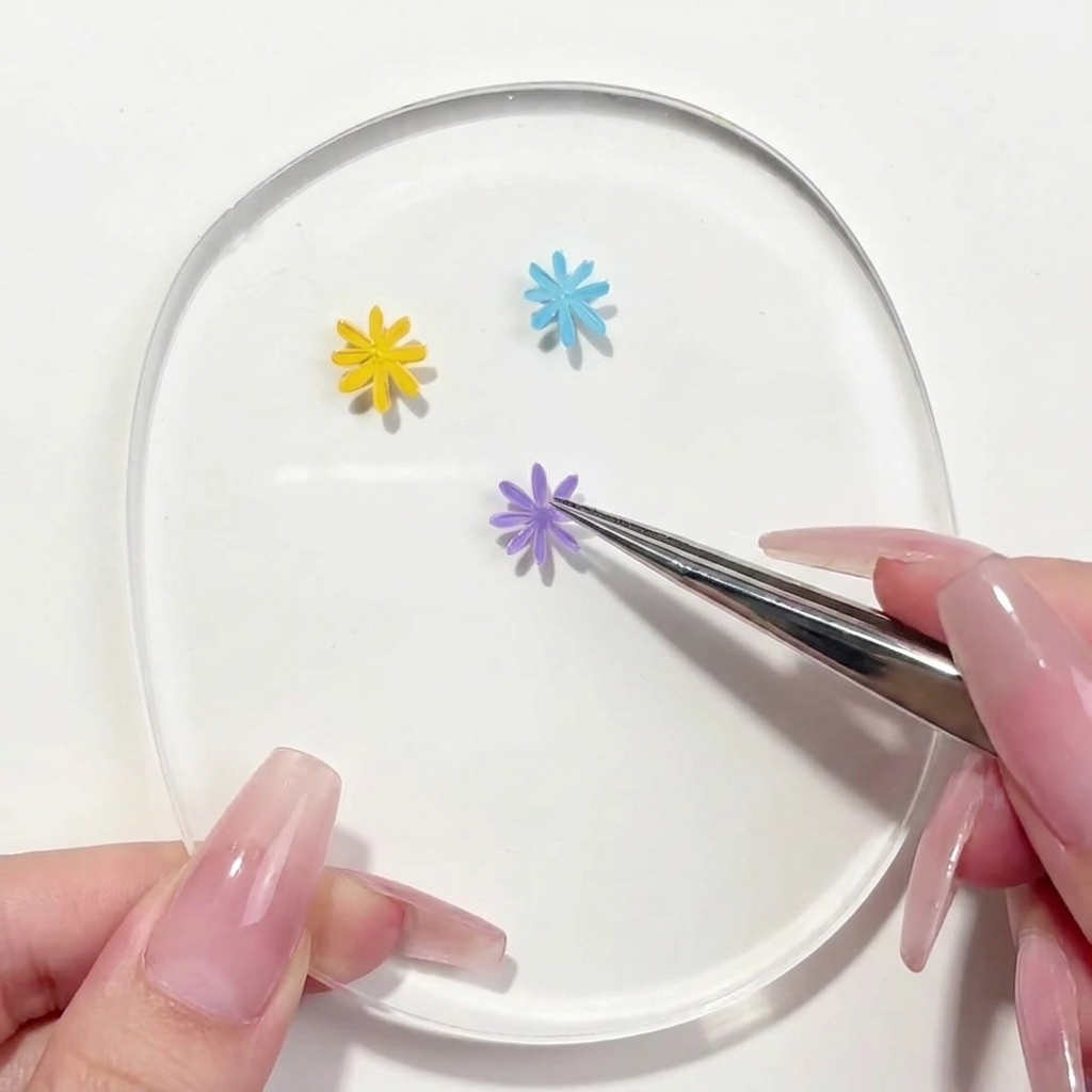 Ein Liner-Pinsel trägt ein zweites violettes Blütenblatt auf das Blumendesign auf der Palette auf.