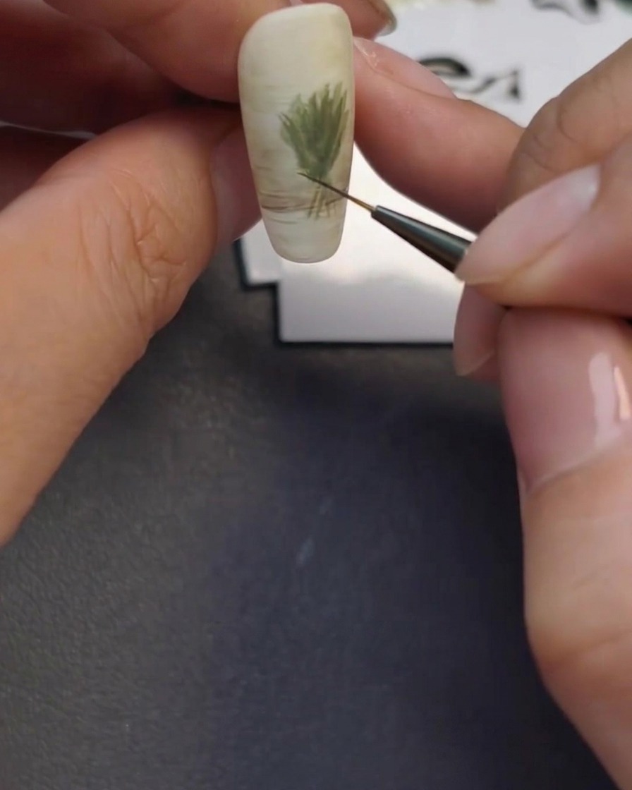 Ein Liner-Pinsel zieht die feine Kontur einer Vase am unteren Nagelrand.
