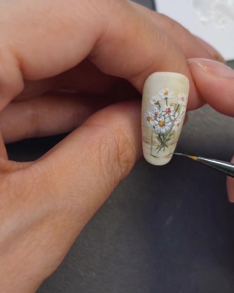 Ein Nageldesigner setzt helle Highlights über den Vasenbereich.