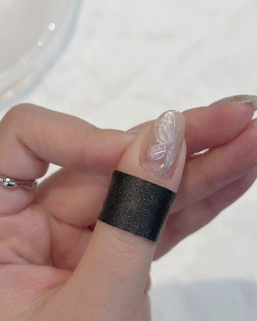 Ein Pinsel schichtet ein dünnes, milchig-weißes Gel über die bereits vorhandenen Blumenblätter.