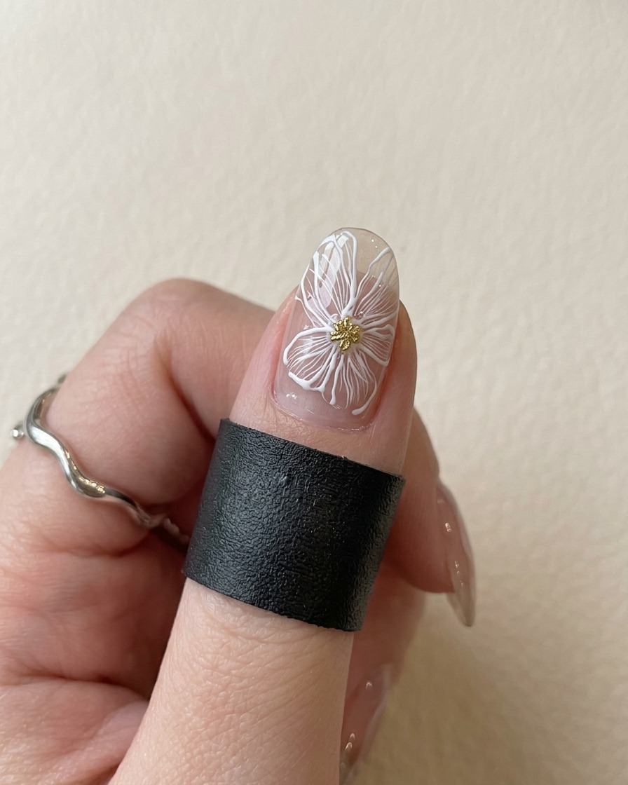 Ein Fingernagel mit einer weißen Blume und goldener Mitte unter einer violetten UV-Lampe beim Aushärten.