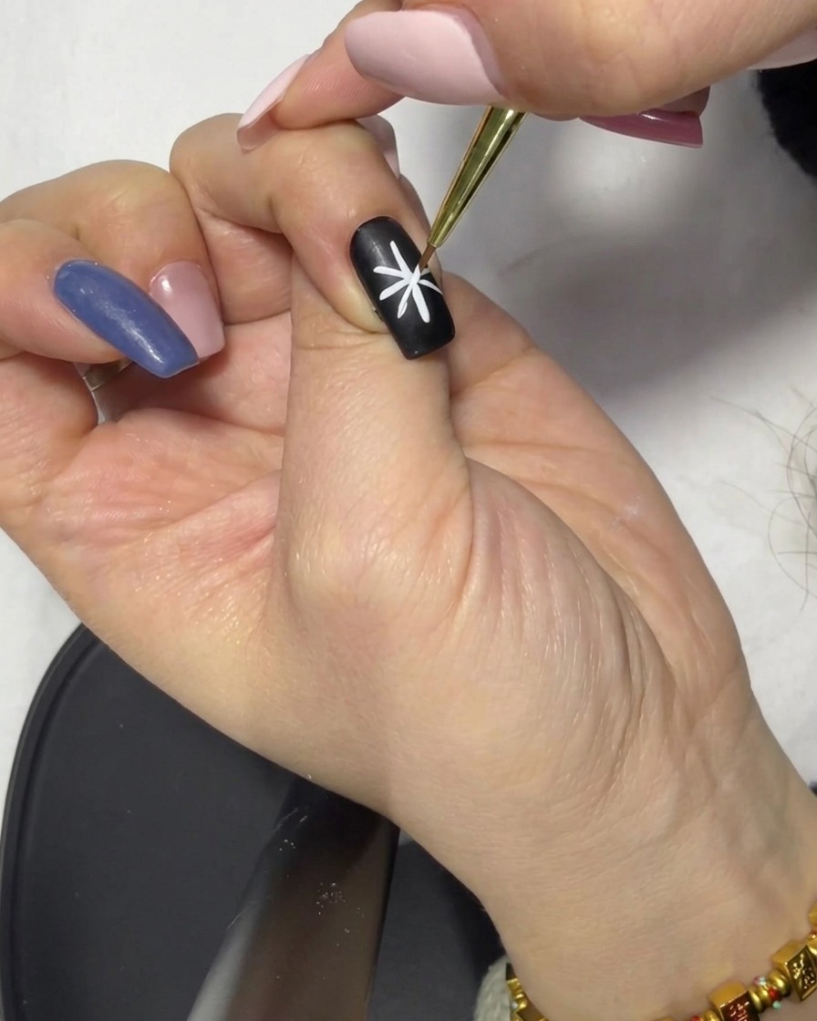 Nahaufnahme eines Fine-Liner-Pinsels, der eine der Linien des Sterns korrigiert, um Symmetrie zu gewährleisten.