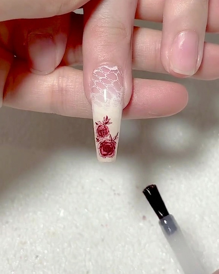Ein Pinsel trägt ein mattes Top Coat auf den gesamten Nagel auf.