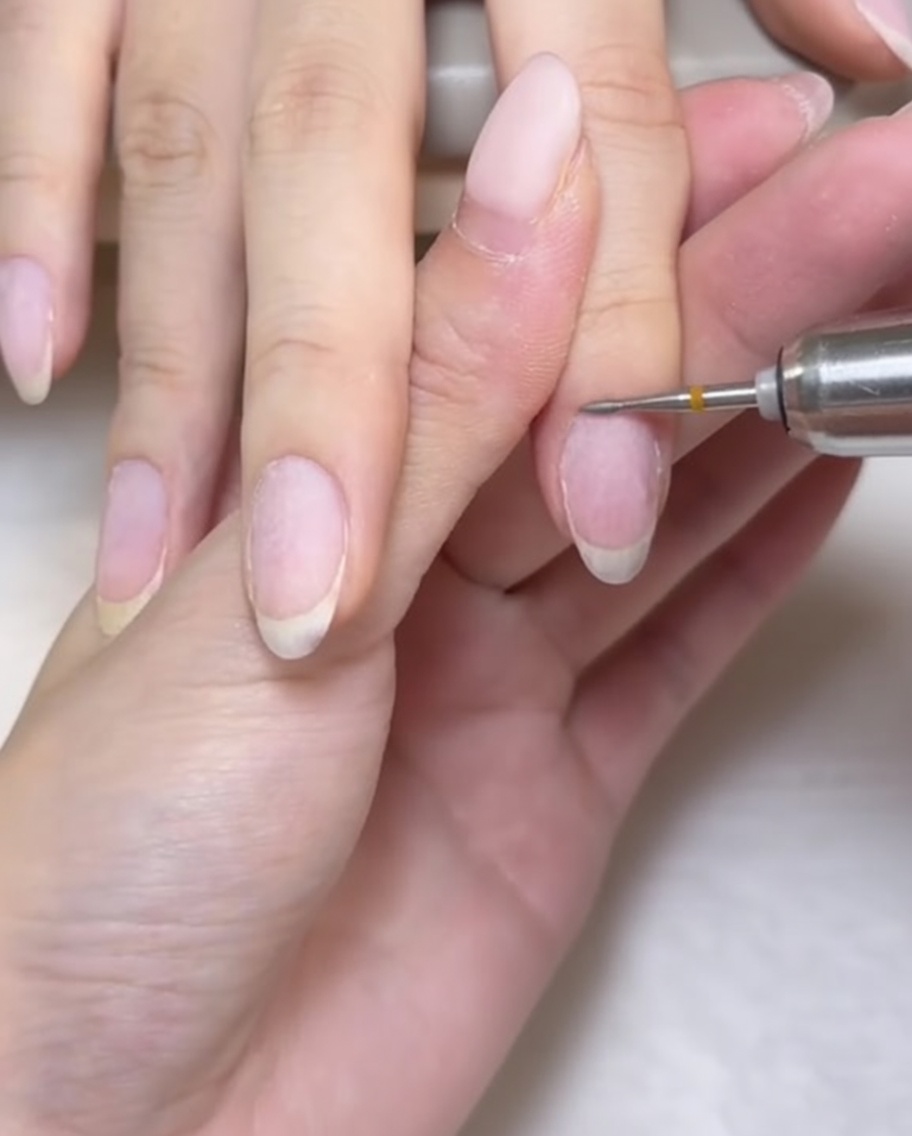 Ein kleiner, abgerundeter hirseförmiger Fräser wird verwendet, um den Nagelhautbereich präzise zu reinigen.