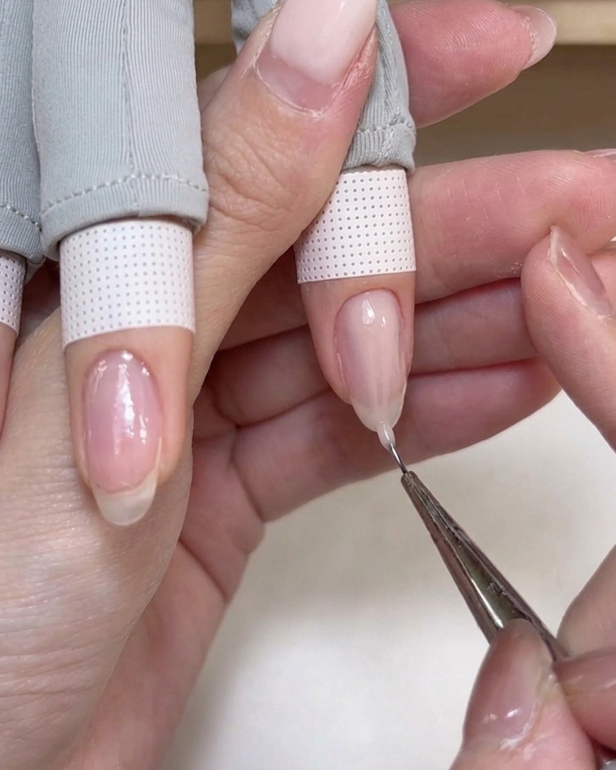 Ein feiner Liner-Pinsel zieht einen Klecks zartrosa Aufbaugel zur Nagelspitze.