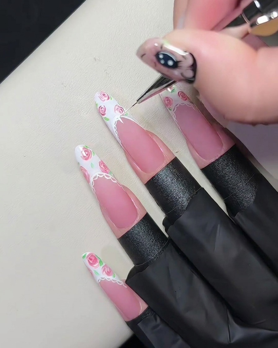Detailansicht eines fertigen Spitzenbordüren-Designs auf einem Nagel, bestehend aus winzigen Halbkreisen und Punkten, die mit einem Präzisionspinsel aufgetragen wurden.