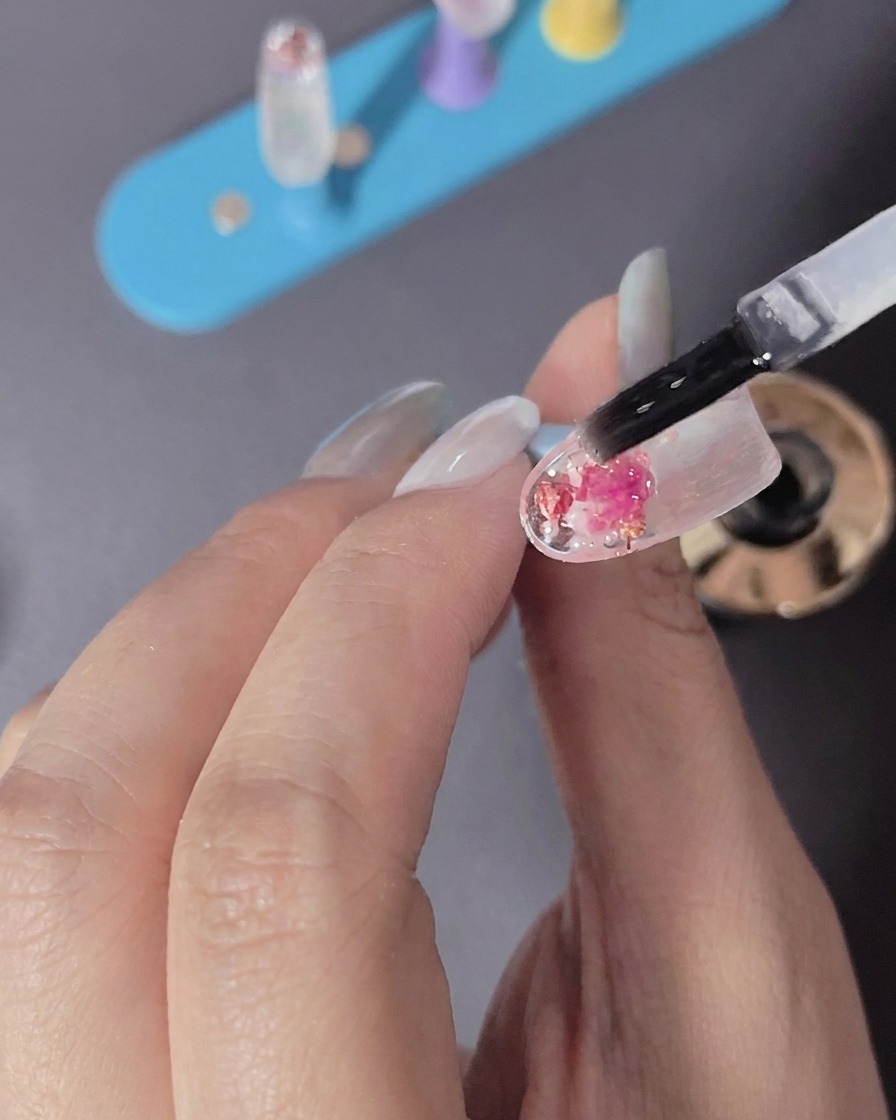 Eine Hand platziert einen Fingernagel unter das Licht einer LED-Lampe.