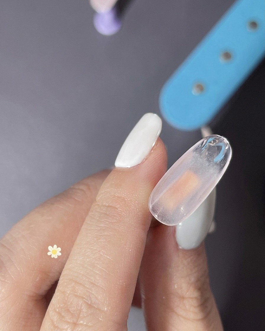 Nahaufnahme: Eine Schicht klares Gel wird auf den Nagel aufgetragen, um ein texturiertes Finish vorzubereiten.