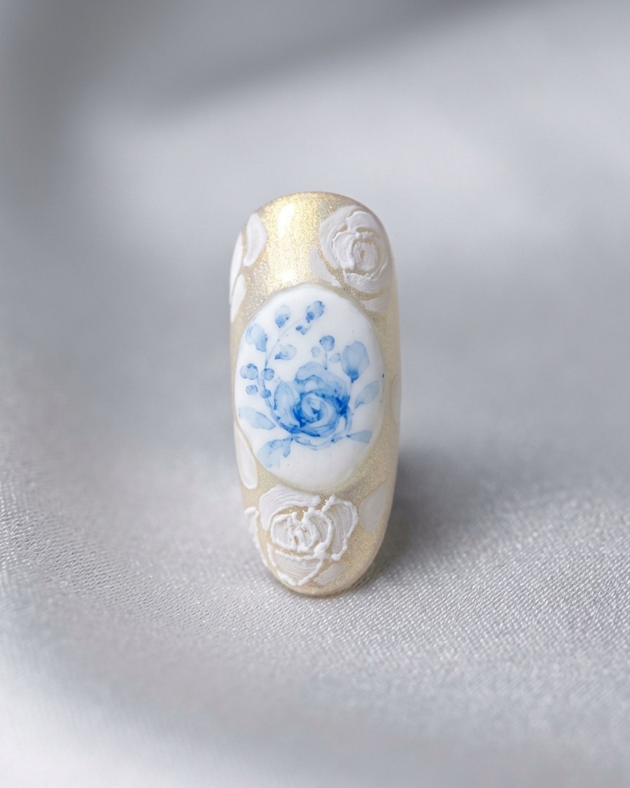 Ein fertiges Nageldesign mit einer zentralen blauen Rose, umgeben von 3D-weißen Rosen und komplexer Spitzenarbeit.