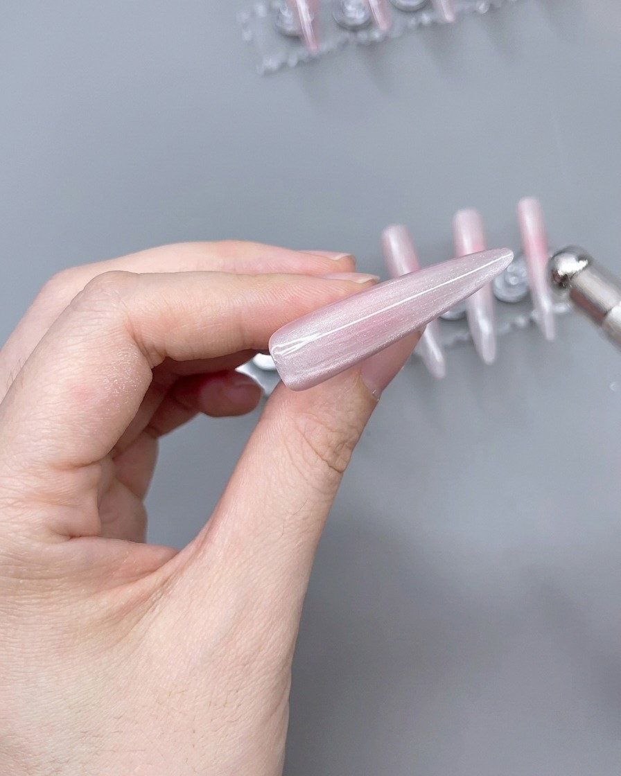 Ein Magnet wird über einen mit Cat-Eye-Gel beschichteten Nageltipp gehalten, um einen schimmernden Lichteffekt zu erzeugen.