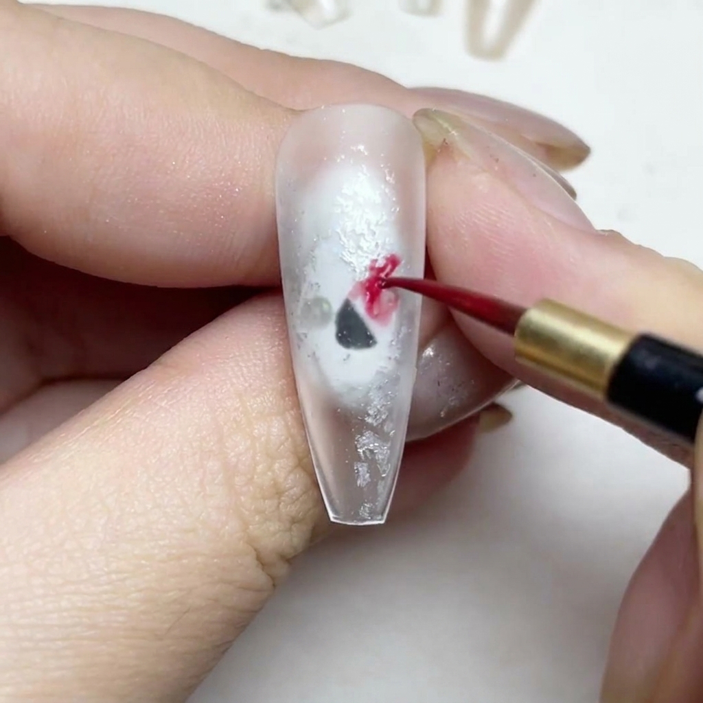 Ein feiner Liner-Pinsel beim Malen roter Aquarell-Rosenblätter auf einem Nagel.