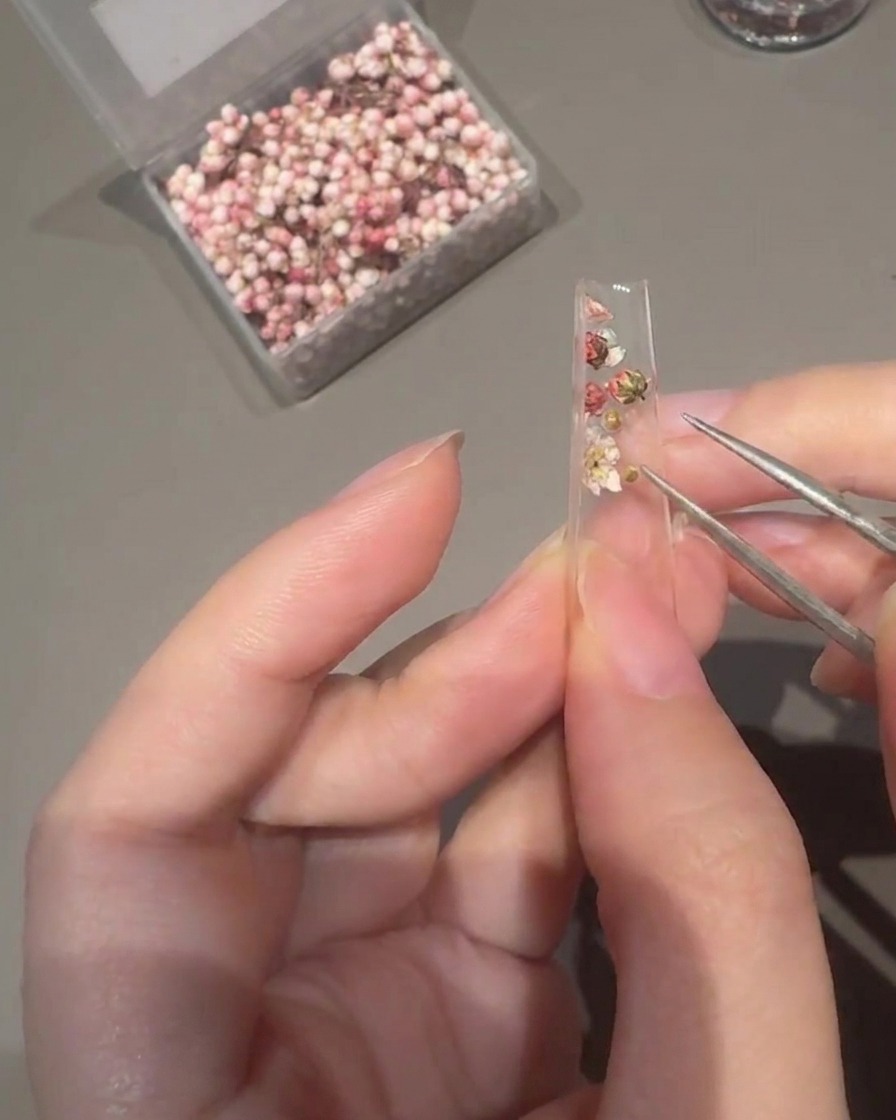 Ein flacher Pinsel trägt klares Aufbaugel über den verzierten Nagel-Tip auf.