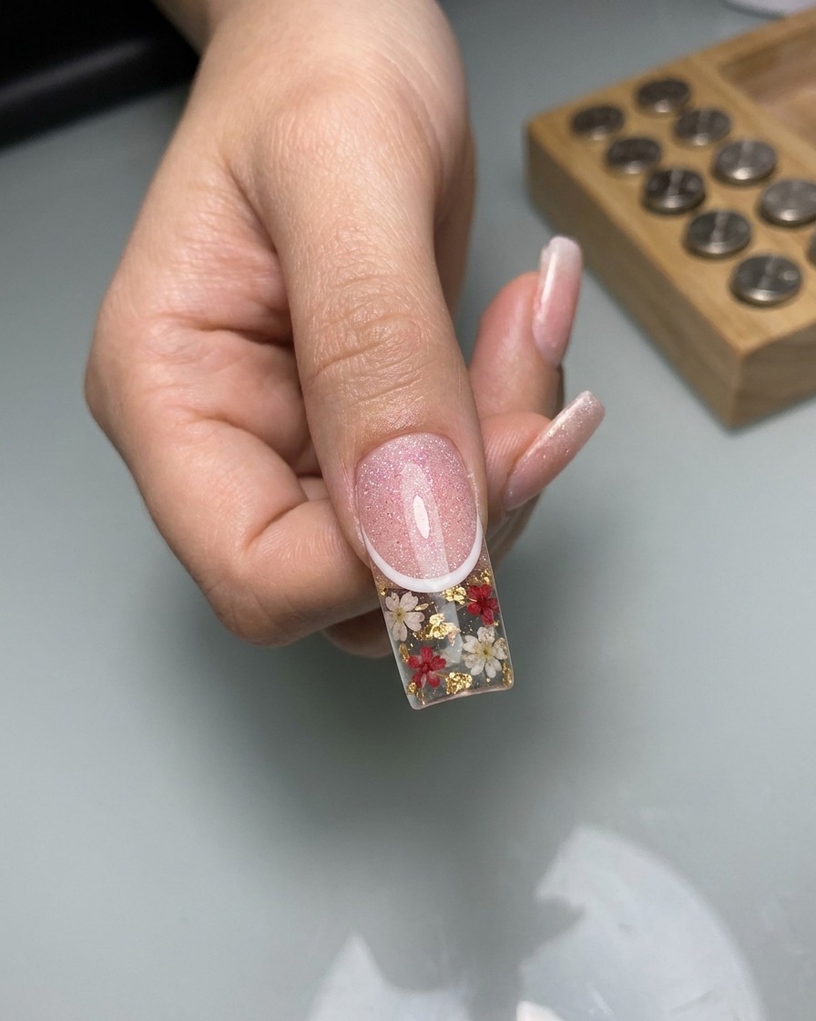 Nahaufnahme eines feinen Liner-Pinsels, der dünne, weiße spitzenartige Linien auf die ausgehärtete Cat-Eye-Nageloberfläche zeichnet.