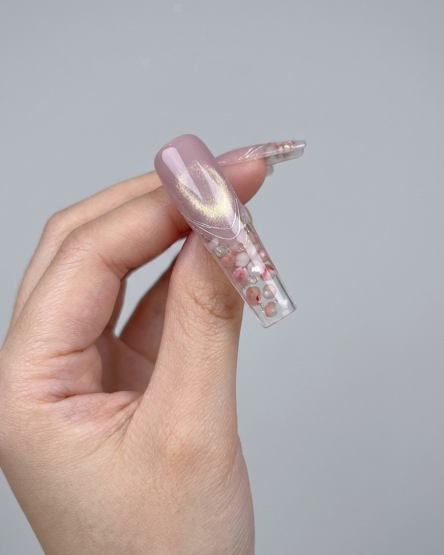 Eine Pinzette platziert eine kleine, funkelnde 3D-Kristallschleife auf einen Nagel.