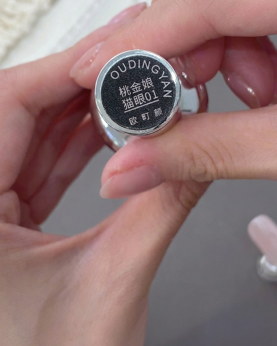 Eine Hand hält eine Flasche mit rosafarbenem Nude Cat-Eye-Gellack.