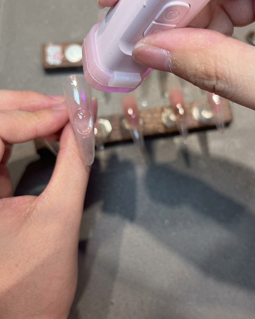 Ein Nageltipp mit Magnetgel zeigt einen diagonalen, schimmernden Lichteffekt an der Seite des Nagels.