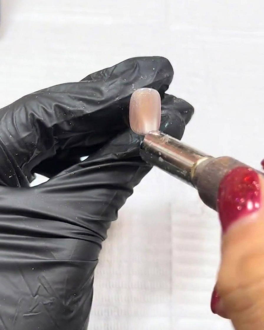 Nahaufnahme, bei der ein Nailart-Magnet über das feuchte Gel gehalten wird, um die Glitzerpartikel mittig zu bündeln.