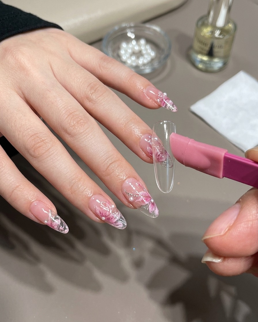 Ein Pinsel trägt goldenes Magnet-Gel auf einen Nageltipp auf.