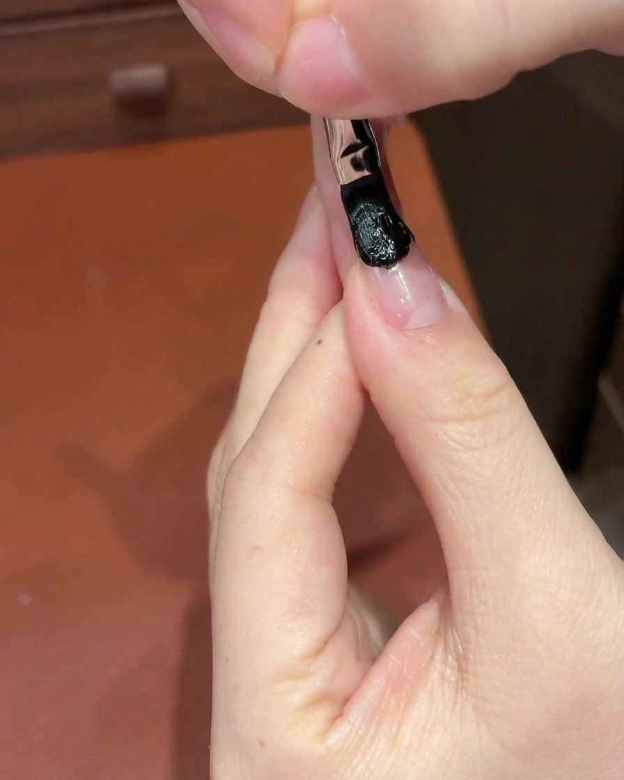 Ein Kosmetikschwämmchen tupft auf den schwarzen Gelbereich am Nagel, um einen Verlauf zu erzeugen.