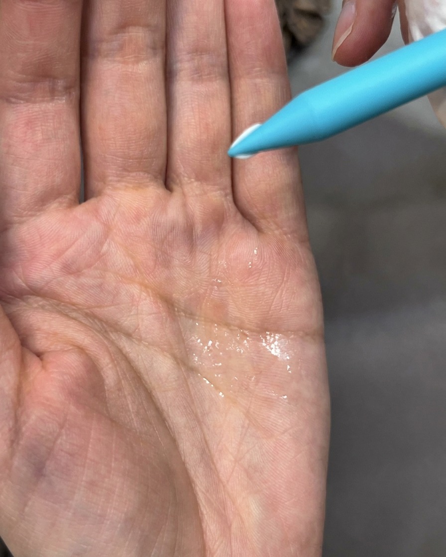 Ein Pinselwerkzeug justiert ein kleines, weißes modelliertes Blütenblatt auf einem Nagel.
