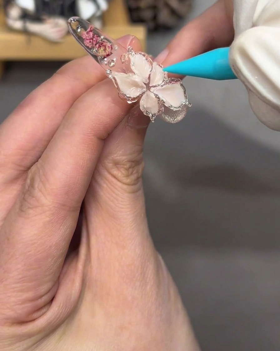 Nahaufnahme des Blumendesigns auf dem Nagel, das nach dem Auftragen von klarem Gelee-Gel glänzend und transparent erscheint.