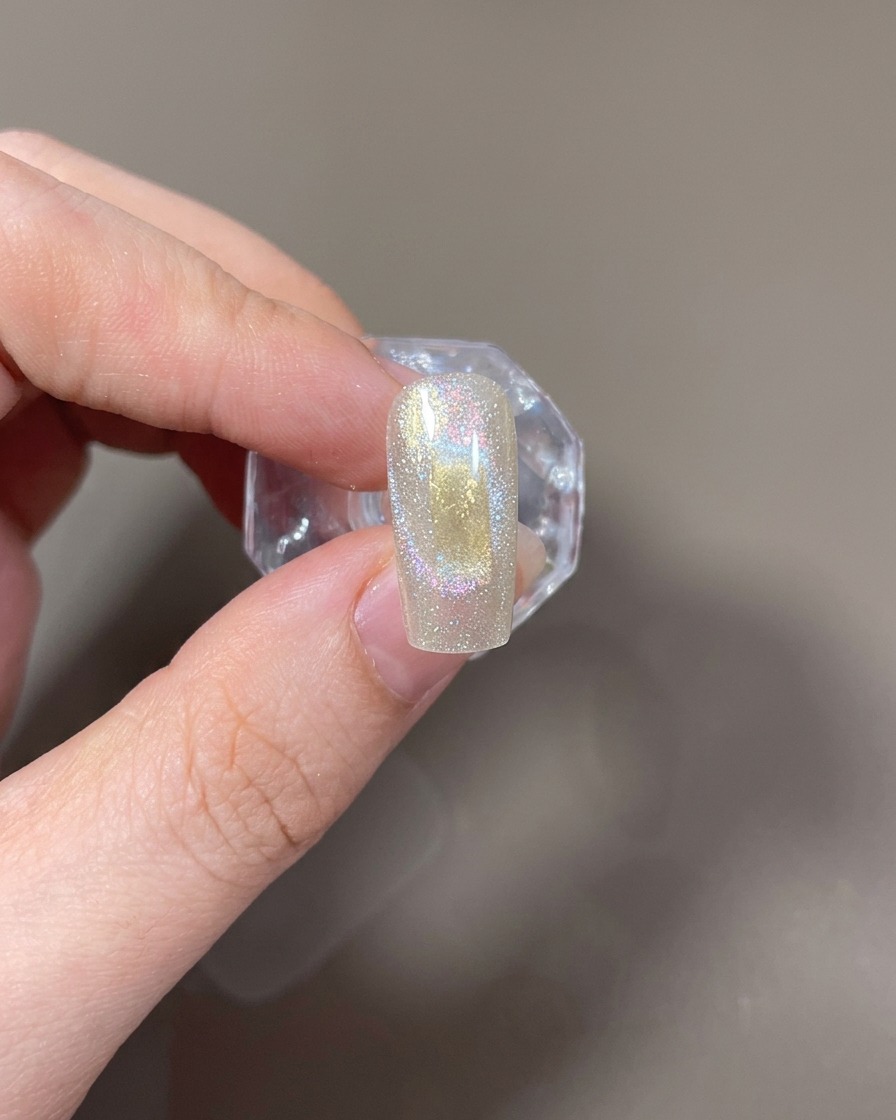 Ein horizontal neben dem Nagel gehaltener rechteckiger Magnet zur Formung eines breiten Cat-Eye-Lichts.
