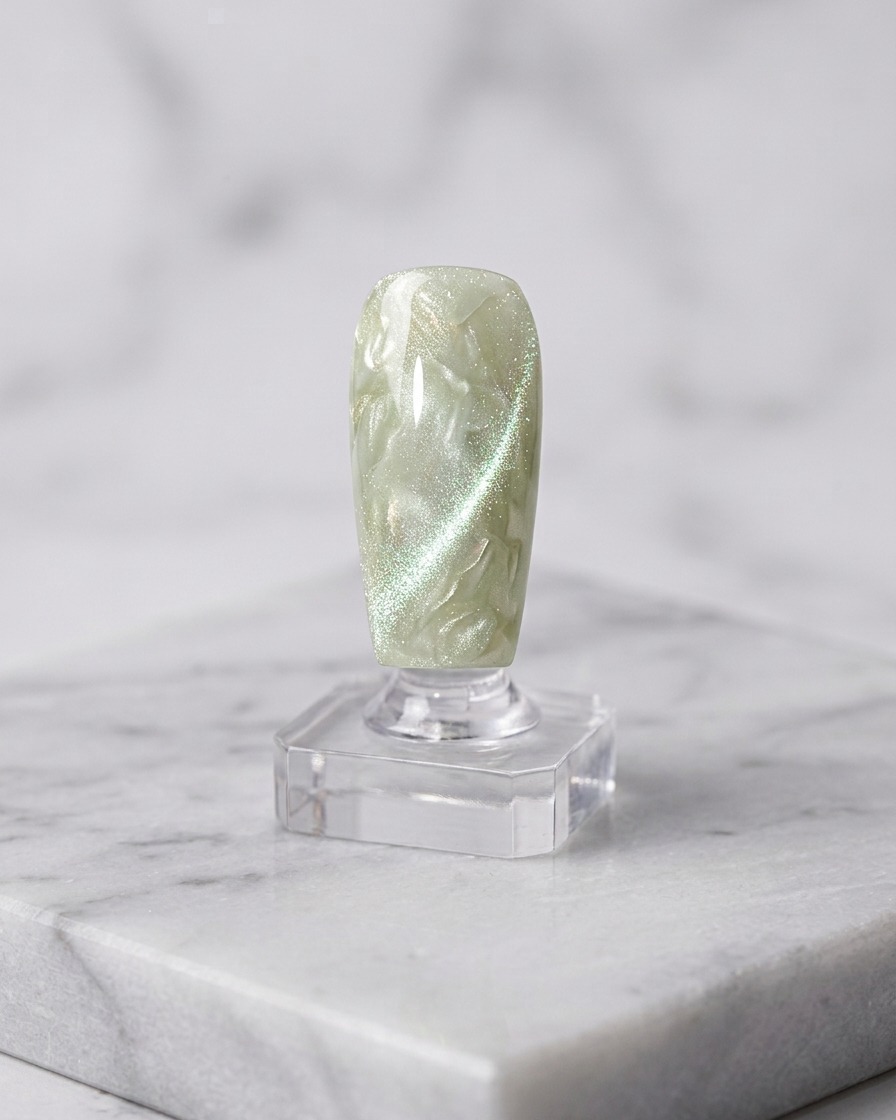 Ein Nagelpinsel trägt eine zweite Schicht Cat-Eye-Gel über der ausgehärteten Basis auf.