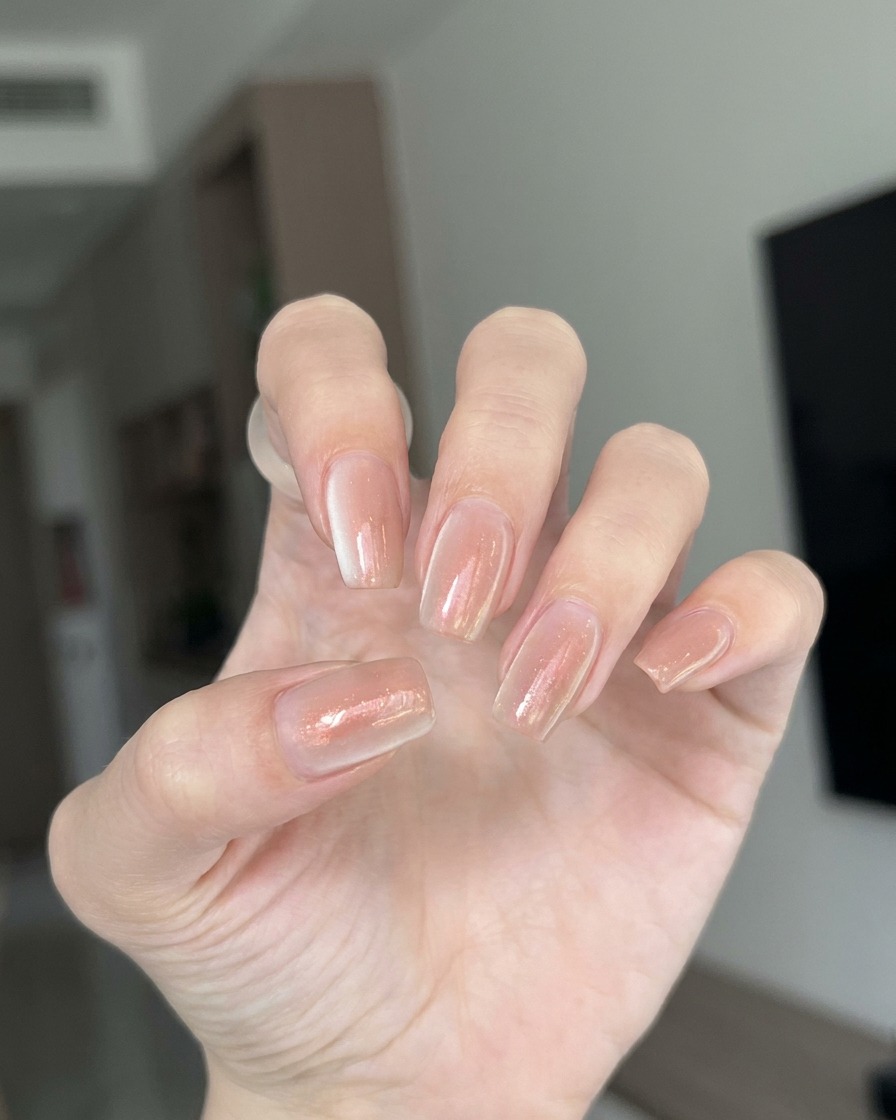 Nahaufnahme eines Pinsels, der eine dünne, klare Schicht Aufbaugel auf eine transparente Nagelverlängerung aufträgt.