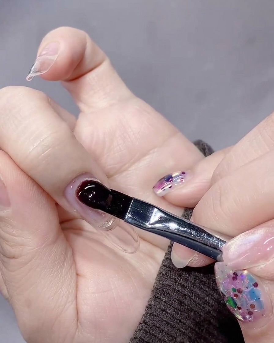 Ein Pinsel platziert eine große, kontrollierte Perle aus Aufbaugel nahe der Nagelhaut.