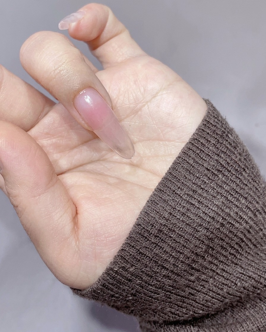 Ein Make-up-Schwamm tupft eine sanfte, pfirsich-orange Farbe auf die Nagelmitte.