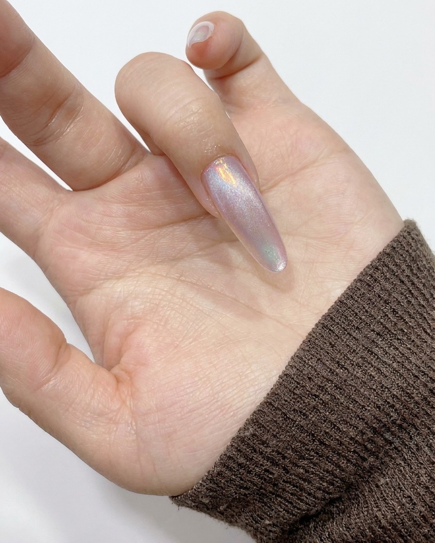 Ein zylindrischer Magnet wird an der Seite eines Nagels gehalten, um den magnetischen Schimmer zum Rand hin zu ziehen.