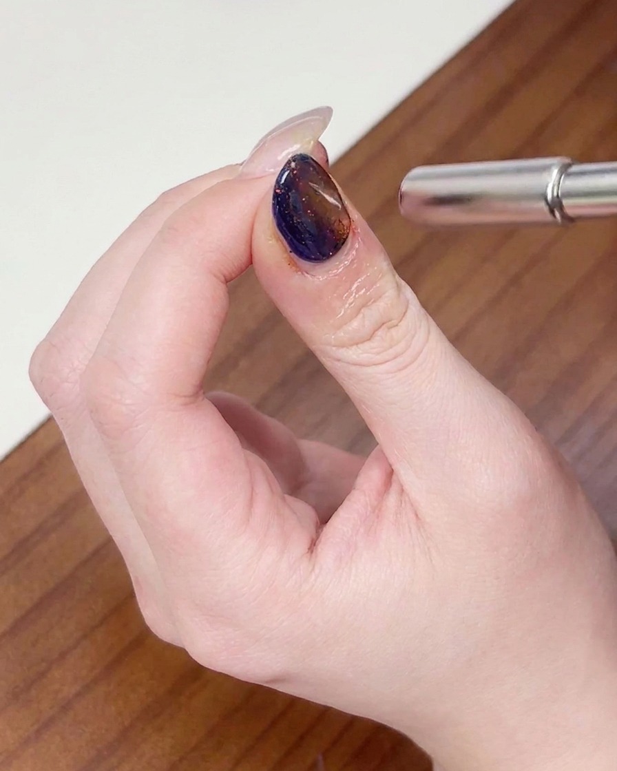 Ein Magnet wird in einer kreisenden Bewegung um die Nagelspitze bewegt, um den Cat-Eye-Schimmer zu formen.