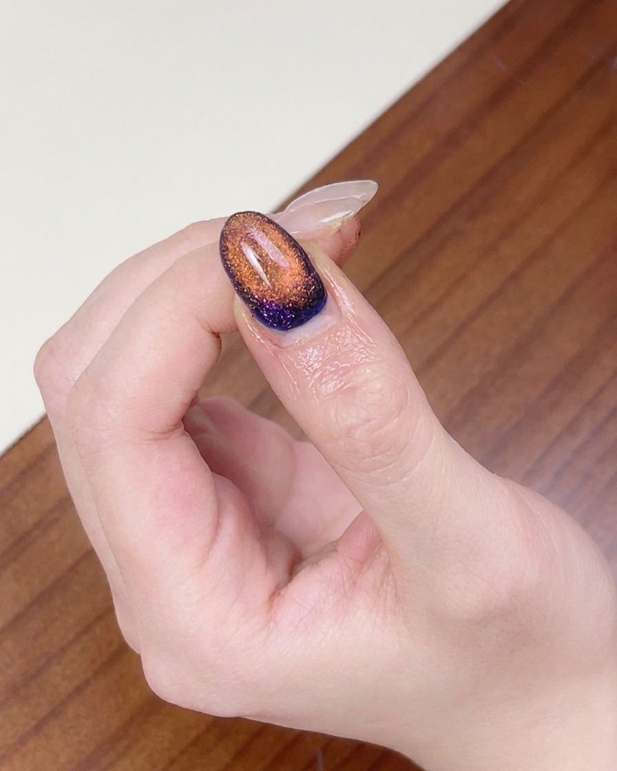 Ein Finger wird unter eine UV-Nagellampe gelegt, um das fertige magnetische Cat-Eye-Nageldesign auszuhärten.
