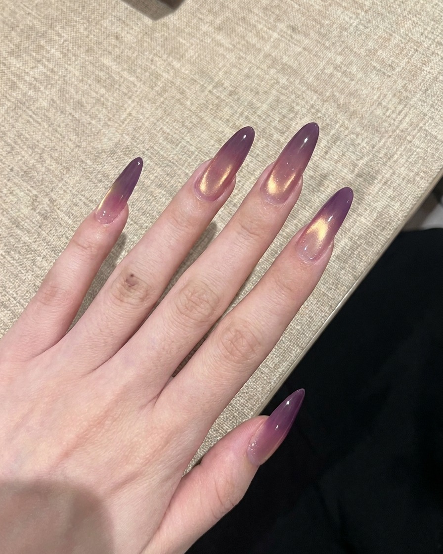 Eine Hand mit fertig lackierten Cat-Eye-Nägeln beim Aushärten unter einer UV-Lampe.