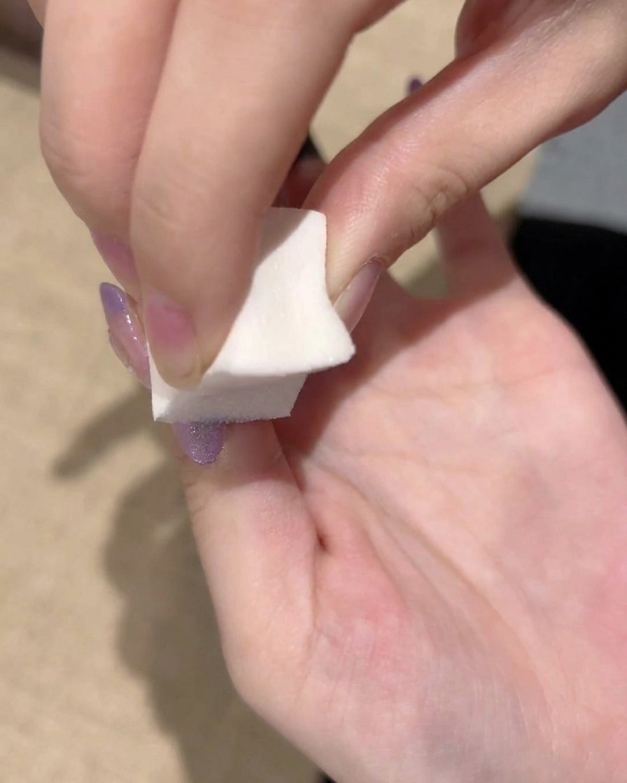 Nahaufnahme eines Schwamms, der wiederholt auf den Übergang des lila Gels klopft, um einen glatten Farbverlauf zu erzielen.