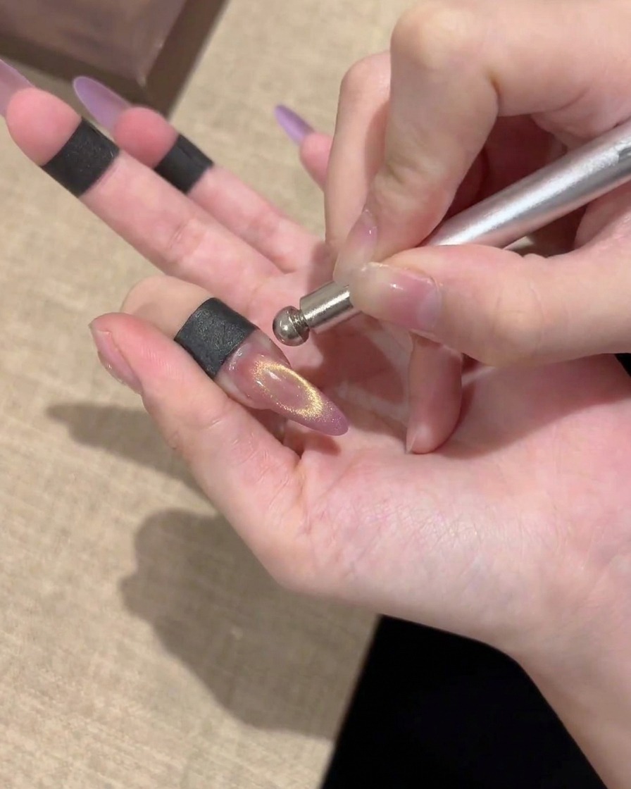Nahaufnahme eines fertigen magnetischen Cat-Eye-Nagels mit einem hellen, zentrierten Gold-Schimmer.