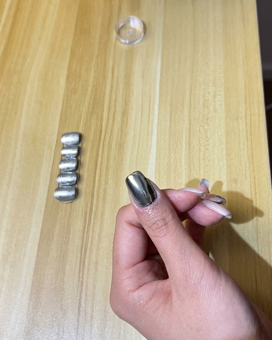 Eine Hand mit Chrom-Nägeln in einer UV/LED-Nagellampe, wobei das Licht eingeschaltet ist.